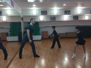 מורה מקצועי לריקודים סלוניים ולטיניים מלמד רקדנים צעירים בשיעור ריקודים פרטי